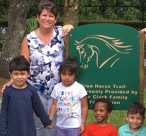 Mom and children smiling in front of a sign